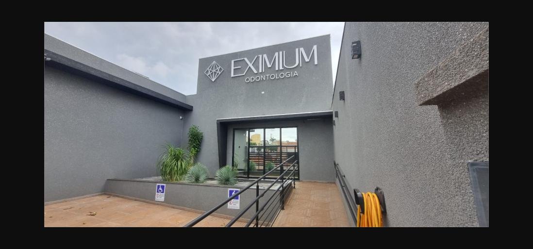 Fachada da Eximium Odontologia com letreiro, jardim e rampa