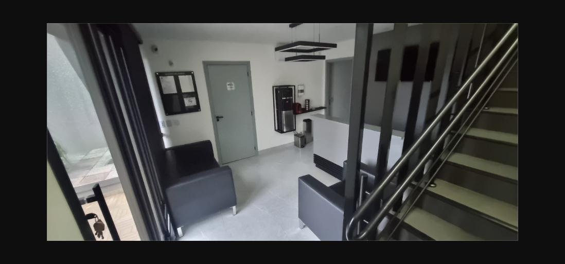 Recepção da clínica com sofás pretos e balcão branco